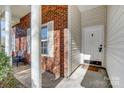 Covered front porch featuring brick columns, a welcome mat and chair on the entry way at 1107 Franklin Thomas Pl, Charlotte, NC 28214