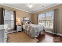 Comfortable bedroom with hardwood floors, ceiling fan, and two windows providing natural light at 16023 Rushwick Dr, Huntersville, NC 28078