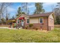 Well-maintained single-story brick home with a covered porch, manicured lawn, and mature trees in background at 198 33Rd Nw St, Hickory, NC 28601