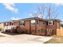 Side view of brick home featuring black shutters, white railings, and a concrete driveway at 703 E Mills Dr, Landis, NC 28088