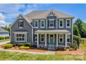 This two-story home features a covered front porch, decorative trim, and beautiful landscaping at 142 Tuscany Trl, Mooresville, NC 28117