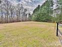 Expansive backyard featuring an open field bordered by mature trees, and a partial fence adding privacy at 2025 Sojourn Rd, Marshville, NC 28103