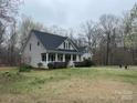 A well-maintained house with gray siding, black shutters, and a welcoming front porch, set on a green lawn at 2025 Sojourn Rd, Marshville, NC 28103