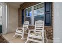 Inviting front porch featuring comfortable chairs and views of brick accents, decorative shutters, and a manicured lawn at 4075 Creekstone Trce, Gastonia, NC 28056