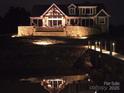 Night exterior view of waterfront home showcasing its stonework and architectural lighting at 5086 Windward Point Ln, Denver, NC 28037