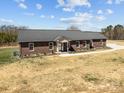 An attractive single-story brick home is presented, showcasing a sleek metal roof and a spacious surrounding yard at 515 Panhandle Rd, Gold Hill, NC 28071