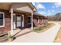 A welcoming brick home featuring a charming front porch with decorative columns and flower pots at 515 Panhandle Rd, Gold Hill, NC 28071