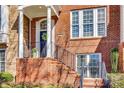 Close-up of a red brick porch with a wrought iron handrail and stairs leading up to a blue front door at 663 Sixth Baxter Xing, Fort Mill, SC 29708