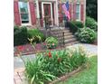 Charming brick home featuring a lovely front porch adorned with colorful flowers and an American flag at 8432 Junction Ct, Charlotte, NC 28215