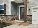 Close-up of the front door with decorative glass, stone accents, and manicured landscaping at 925 Deep River Way, Waxhaw, NC 28173