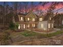 A beautiful two story home featuring a stone facade, siding, and manicured lawn highlighted by a colorful sunset at 109 Hawksnest Ln, Mooresville, NC 28117
