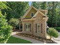 A side view of this lovely home shows stone facade, attractive windows, and meticulously landscaped beds with verdant trees at 109 Hawksnest Ln, Mooresville, NC 28117