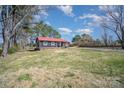 Cozy home with a red roof and spacious yard, surrounded by mature trees in a quiet neighborhood at 127 Barry Oak Rd, Statesville, NC 28625