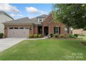 Charming brick home features a manicured lawn, attached garage, and inviting front entrance with manicured landscaping at 12726 Rusty Blackbird Way, Charlotte, NC 28278