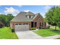 Charming brick home features a manicured lawn, attached garage, and inviting front entrance with manicured landscaping at 12726 Rusty Blackbird Way, Charlotte, NC 28278