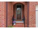 Close-up view of front door with brick archway, potted plants, and welcome mat at 16620 Redding Park Ln, Cornelius, NC 28031