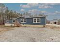 Inviting single-story home with blue siding, a wooden porch, large windows, and metal building at 2647 Dusty Trail Ln, Lancaster, SC 29720