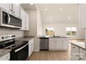 Modern kitchen with stainless steel appliances, granite countertops, white cabinets and light wood floors at 3516 Narrow Ln, Charlotte, NC 28215