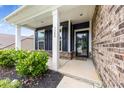 Inviting covered front porch with white columns, dark siding and brick accents at 1300 Dali Blvd, Mount Holly, NC 28120