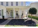 Inviting front porch with white columns, curtains, seating, and manicured landscaping for curb appeal at 18948 Kanawha Dr, Cornelius, NC 28031