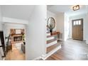 Bright foyer with wooden floors and stairs, complemented by a stylish mirror and front door at 5019 Crooked Oak Ln, Charlotte, NC 28226