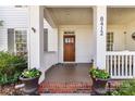 Inviting front porch with craftsman columns, decorative flower pots, and house number at 8412 Westmoreland Lake Dr, Cornelius, NC 28031