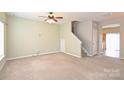 An open living room with beige carpet, ceiling fan and a staircase leading to the second floor at 10422 Stokeshill Ct, Pineville, NC 28134