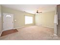 Bright living room with a light colored door, large window and carpeted floors at 10422 Stokeshill Ct, Pineville, NC 28134