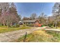 Quaint brick home with a classic design, complemented by mature trees and a side deck at 1235 Robinhood Cir, Charlotte, NC 28227