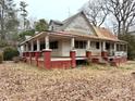 Home showcasing a covered porch with brick supports and mature trees in a wooded setting at 2412 Daves Dr, Shelby, NC 28152