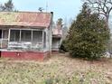 Exterior view with aged facade, screened porch, and mature landscaping, presenting a fixer-upper opportunity at 2412 Daves Dr, Shelby, NC 28152