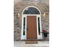 Close-up of front door framed by brick, sidelights, and a transom window, enhanced with sconces and a potted plant at 7306 Timbercreek Ct, Denver, NC 28037