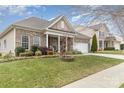 Well-maintained brick home with inviting front porch, white columns, and lush landscaping creating curb appeal at 9795 Shearwater Nw Ave, Concord, NC 28027