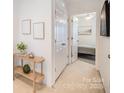 Inviting hallway featuring white walls, carpet, decorative art, and a glimpse into a bright bedroom at 10530 Stoneacre Ct, Pineville, NC 28134