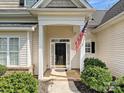 Close-up of the front door with classic details, an American flag, and manicured landscaping at 1394 Fitzgerald Nw St, Concord, NC 28027