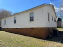 Side exterior of home with neutral siding and visible foundation, set against a clear blue sky at 216 W Shannonhouse St, Shelby, NC 28152
