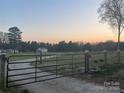 Property gate, with a gravel drive, set against a colorful twilight sky at 485 Harper Miller Dr, Cleveland, NC 27013