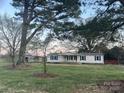 Exterior view of a white house with blue shutters, a covered porch, and well-maintained lawn surrounded by mature trees at 485 Harper Miller Dr, Cleveland, NC 27013