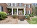 Inviting covered front porch featuring classic brick steps, white columns, hanging ferns, and a wood-look front door at 518 Streamside Ln, Marvin, NC 28173
