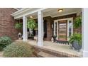 Charming covered front porch adorned with hanging plants, neutral furniture, and an elegant front door with glass panels at 518 Streamside Ln, Marvin, NC 28173