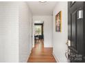 Inviting home foyer featuring hardwood floors and a white painted brick wall, creating a modern, stylish entrance at 5435 Farmbrook Dr, Charlotte, NC 28210