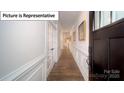 Elegant hallway featuring hardwood floors, wainscoting, and a striking dark wood front door at 7015 Sylvan Retreat Dr, Denver, NC 28037