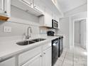 Well-lit kitchen with stainless steel sink, white cabinets, and black appliances at 7415 Mystic Ln, Charlotte, NC 28227