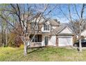 Charming two-story home with a brick and siding exterior, covered porch, and attached garage at 10820 Hunters Trace Ct, Charlotte, NC 28262