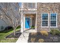 Inviting entrance with a bright blue door, stone accents, and manicured landscaping at 13925 Helen Benson Blvd, Davidson, NC 28036