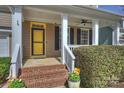 Inviting front porch featuring brick steps, white railings, and a vibrant yellow door at 142 Mills Ln, Fort Mill, SC 29708