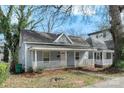 Cozy one-story house with a covered front porch and light blue siding, set amongst mature trees at 314 Flint St, Charlotte, NC 28216