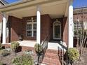 Close-up of a brick home's front porch with stately columns and wrought-iron railings, offering classic appeal at 315 Drake Park Ave, Fort Mill, SC 29708