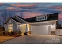 Beautiful single-Gathering home at dusk featuring stone accents, a two-car garage, and a well-manicured front yard at 5367 Heartwood Ln, Denver, NC 28037