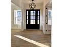 Inviting entryway features a stylish front door, chandelier, wood floors, and detailed trim work at 8827 Wingard Rd, Waxhaw, NC 28173